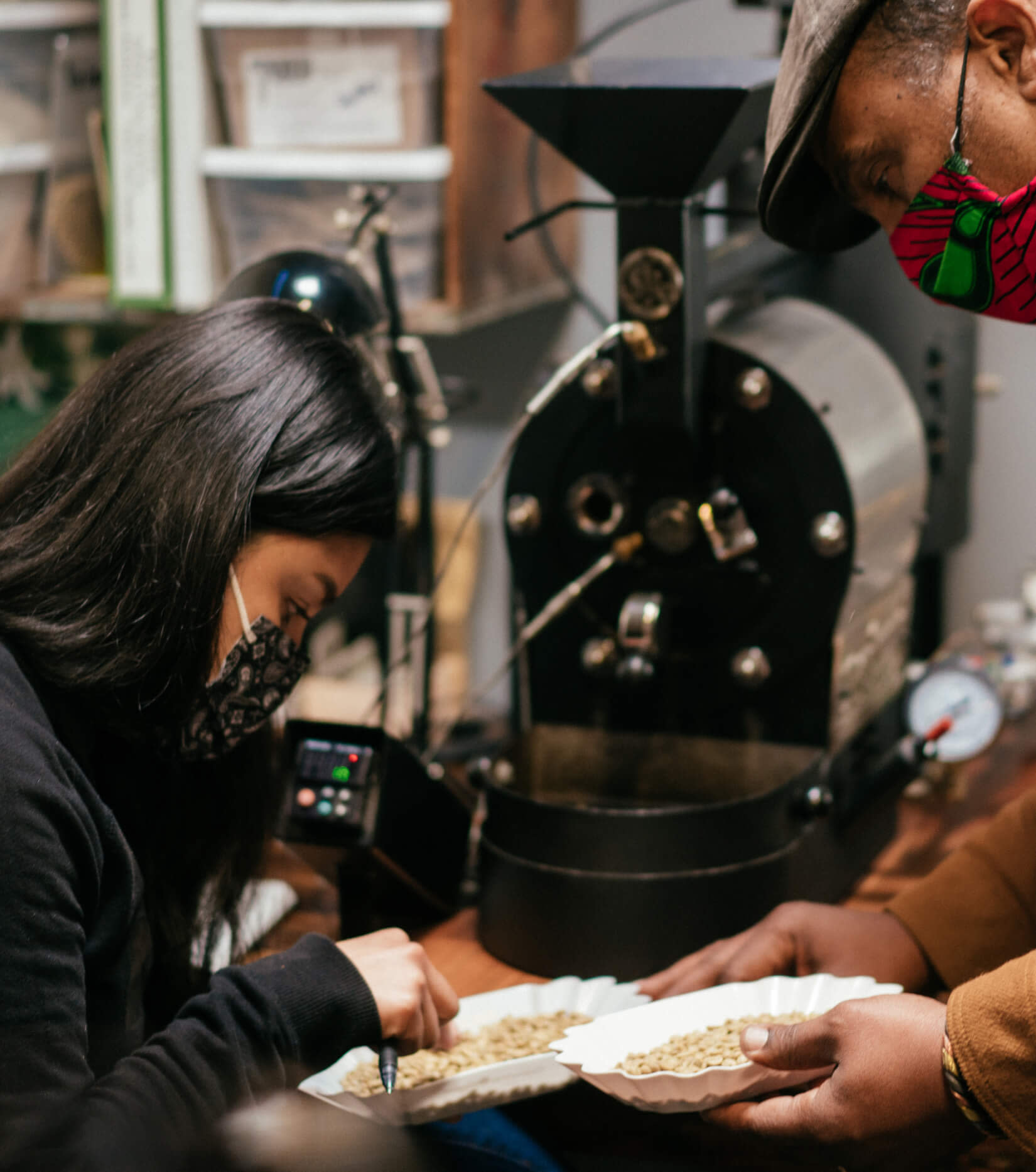 Keba Konte, fundador de Red Bay Coffee, y un empleado revisan los granos de café crudos.
