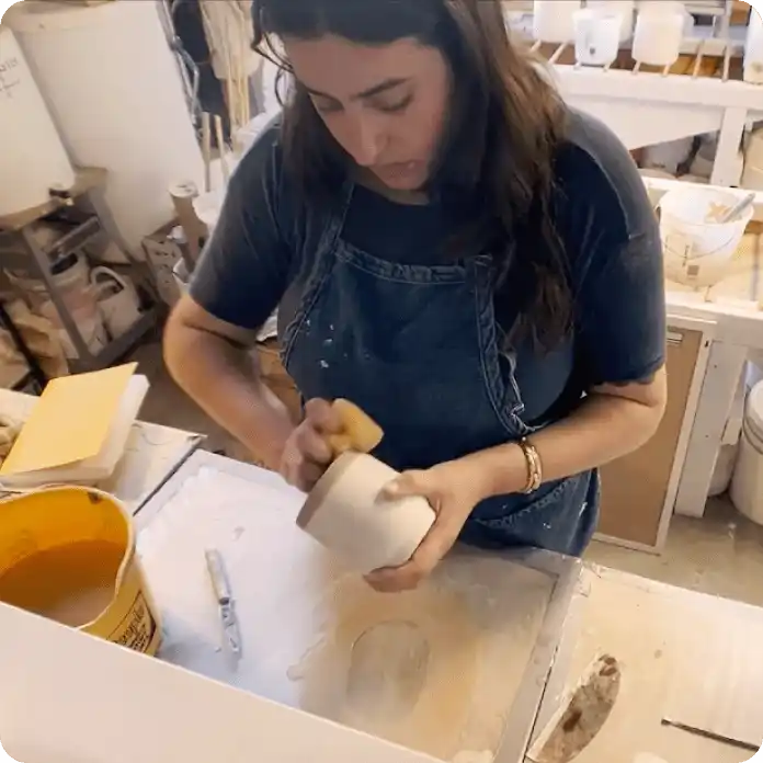Ceramics business owner makes a mug out of clay in her studio